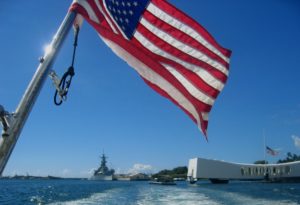 United States of America flag flying above the USS Arizona Memorial in Pearl Harbor on the island of Oahu.