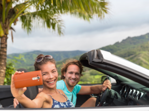 Couple having fun on summer vacation road trip taking smartphone pictures during travel.